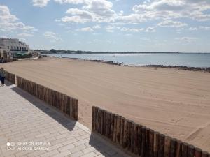a sandy beach next to the ocean with a wooden fence at LEVANTE APPARTAMENTO SUL MARE in Porto Cesareo