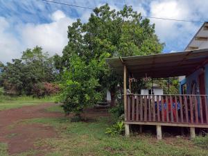 una casa con porche de madera junto a un árbol en Cabañas Henua Roa en Hanga Roa