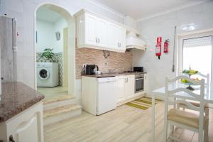 a kitchen with white cabinets and a washer and dryer at casa saloia in Nazaré