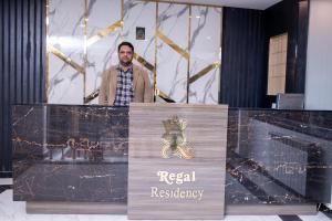 un hombre de pie detrás de un podio con una señal de registro real en Regal Residency en Rawalpindi