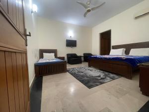 een kamer met 2 bedden, een stoel en een televisie bij Dream Palace in Islamabad