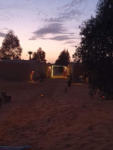 una puesta de sol en un desierto con un edificio en el fondo en SaharaTime Camp, en Adrouine