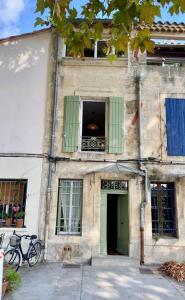 un edificio antiguo con una puerta verde y una ventana en "La paisible" Maison vue sur le Rhône Arles, en Arles