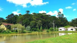 a river with houses and trees in the background at Pousada Mato Verde - Urubici - SC in Urubici