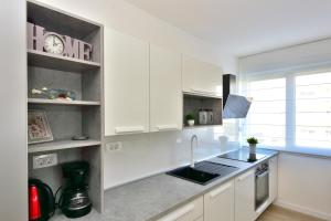 a kitchen with white cabinets and a sink at Apartman MAIA in Split