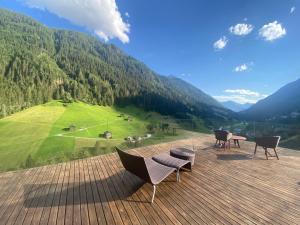 una terraza con sillas y mesas y vistas a la montaña en Schooren des Alpes Luxury Apartments, en Kappl