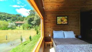 a room with a bed and a view of a river at Pousada Mato Verde - Urubici - SC in Urubici