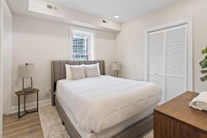 a white bedroom with a large bed and a window at Loopin Around Atlantic City Luxe 5BR Townhouse in Orange Loop in Atlantic City