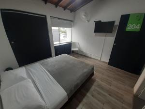 1 dormitorio con cama blanca y ventana en Cocobamboo Hotel, en Medellín