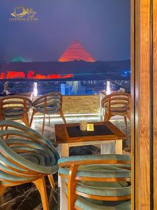 a table and chairs with a view of a pyramid at Cleopatra Pyramids View in Cairo