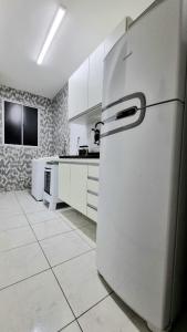 a white kitchen with a refrigerator in a room at Apartamento aconchegante, em uma das praias mais bonitas do ES in Serra