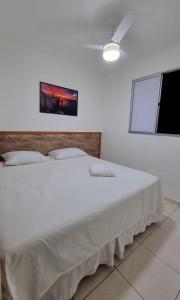 a bedroom with a large white bed with a picture on the wall at Apartamento aconchegante, em uma das praias mais bonitas do ES in Serra