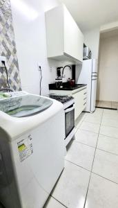 a kitchen with white cabinets and a white floor at Apartamento aconchegante, em uma das praias mais bonitas do ES in Serra