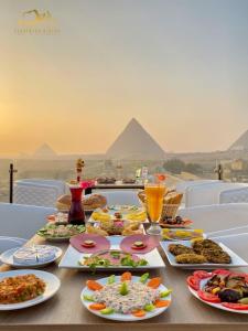 uma mesa com pratos de comida com ramids no fundo em Cleopatra Pyramids View em Cairo