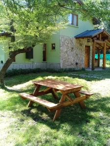 a wooden picnic table in front of a house at Cabañas Shalom in Lago Puelo