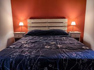 a bedroom with a bed with a blue comforter and two lamps at Cabañas Shalom in Lago Puelo