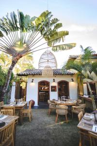 un restaurante con mesas, sillas y una palmera en Casa Flô, en Porto Seguro