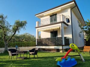 una casa con cortile attrezzato con sedie e parco giochi di La Chianarella ad Ascea