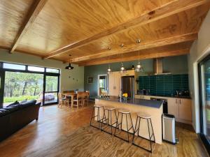 an open kitchen and living room with wooden ceilings at Hahei Hideout Retreat in Hahei