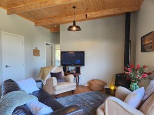 a living room with a couch and chairs and a tv at Hahei Hideout Retreat in Hahei