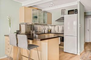 a kitchen with a white refrigerator and two chairs at Dinbnb Apartments I Charming 3-Bedroom in the Heart of the City in Bergen