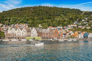 a boat in the water in front of a city at Dinbnb Apartments I Charming 3-Bedroom in the Heart of the City in Bergen