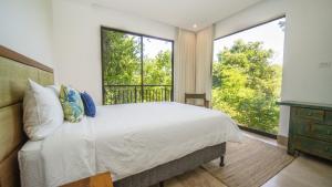 ein Schlafzimmer mit einem Bett und einem großen Fenster in der Unterkunft Roble Sabana 105 Luxury Apartment - Reserva Conchal in Playa Conchal