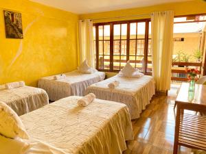 3 camas en una habitación con paredes amarillas en Esperanza Hotel - Oxapampa, en Oxapampa