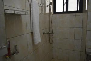 ein Bad mit einer Dusche und einem an der Wand hängenden Handtuch in der Unterkunft BWAMI DUBAI HOTEL KASULU 