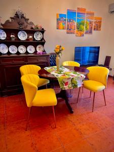 een eetkamer met een tafel en gele stoelen bij La Fontanella Apartment in Taormina