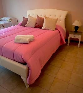 een groot bed met roze dekens en kussens erop bij La Fontanella Apartment in Taormina