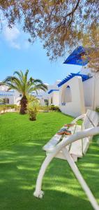 米多恩的住宿－Zenon Djerba，院子里的白色长凳和雨伞
