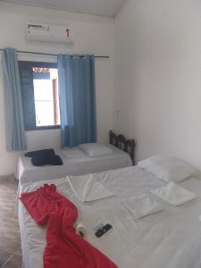 um quarto com 2 camas e um roupão vermelho na cama em Pousada Edson em Caraguatatuba