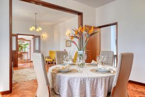 Casa do Valentim, a Home in Madeira في بونتا دو سول: طاولة غرفة الطعام مع إناء من الزهور عليها