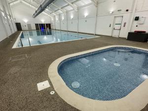 a large swimming pool in a large building with a swimming pool at Dragonfly Cottage in Filey