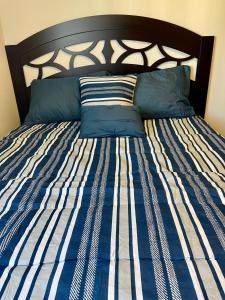 Cama con sábanas y almohadas de rayas azules y blancas en Apartamento en Ecovivienda Fase 2 Tegucigalpa, en Tegucigalpa