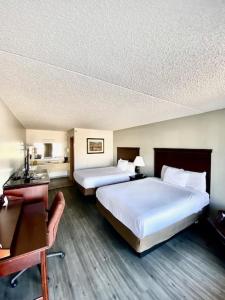 a hotel room with two beds and a desk at Willow Tree Inn Branson in Branson