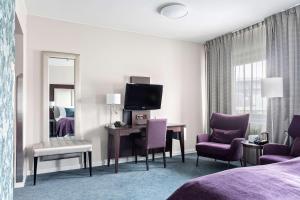 una camera d'albergo con letto e scrivania con sedie viola di Best Western Plus Gyldenlove Hotell a Kongsberg