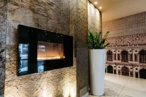 una pared con TV y un jarrón con una planta en Best Western Hotel Tre Torri, en Altavilla Vicentina