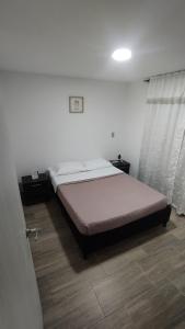 een slaapkamer met een bed in een witte kamer bij Hermoso Apartamento en Circasia, Quindío. in Circasia