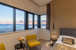 Seascape Luxury Rooms في سبليت: غرفة نوم بسرير وكرسي ونوافذ