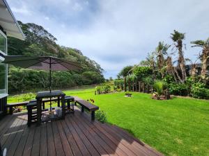 a wooden deck with a table and an umbrella at Hot Water Beach Escape in Hotwater Beach