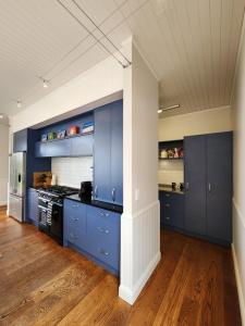 a large kitchen with blue cabinets and wooden floors at Hot Water Beach Escape in Hotwater Beach +16 photos