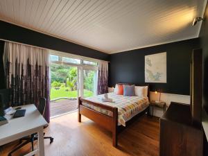 a bedroom with a bed and a large window at Hot Water Beach Escape in Hotwater Beach