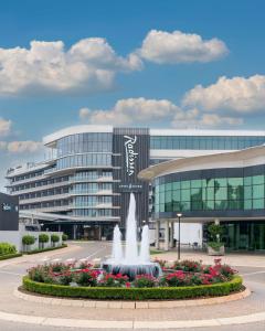 a large building with a fountain in front of it at Radisson Hotel & Convention Centre Johannesburg, O.R. Tambo in Johannesburg