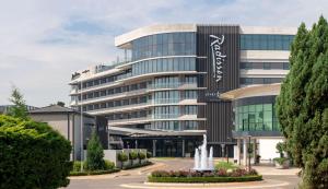 un grand bâtiment avec une fontaine devant lui dans l'établissement Radisson Hotel & Convention Centre Johannesburg, O.R. Tambo, à Johannesbourg