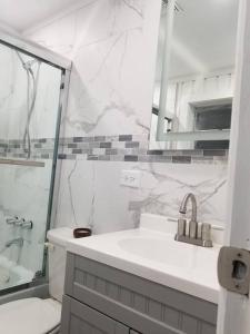 a white bathroom with a sink and a shower at Beautiful cottage near Lake Louisa & mins from Disney, Vehicle Rental Available in Clermont