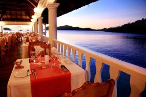 a dining room table with a balcony overlooking the ocean at Le Domaine de La Reserve in Baie Sainte Anne