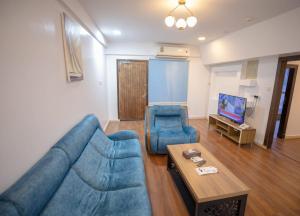a living room with a blue couch and two chairs at Yar Furnished Apartments in Jazan