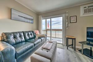 a living room with a leather couch and a television at Chic Oceanfront North Topsail Beach Condo with Deck in North Topsail Beach